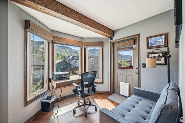 office featuring baseboards, hardwood / wood-style floors, beamed ceiling, and a textured wall
