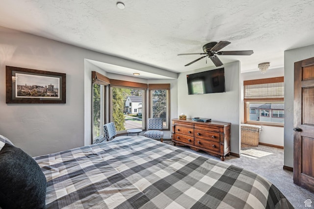 bedroom with a textured ceiling, carpet, baseboards, and a ceiling fan
