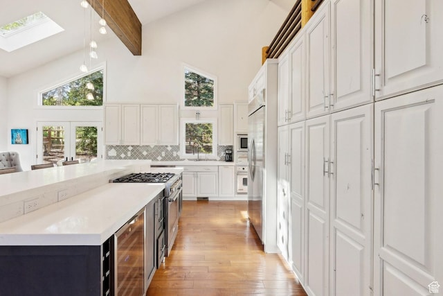 3339 W Big Spruce Way, Park City, UT 84098 - kitchen with beverage cooler, white cabinets, high vaulted ceiling, light wood-style flooring, and a skylight