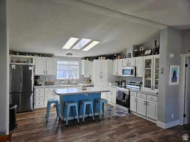 550 S Stump Hollow Rd, Garden City, UT 84028 - kitchen featuring stainless steel appliances, a skylight, white cabinetry, a breakfast bar, and lofted ceiling