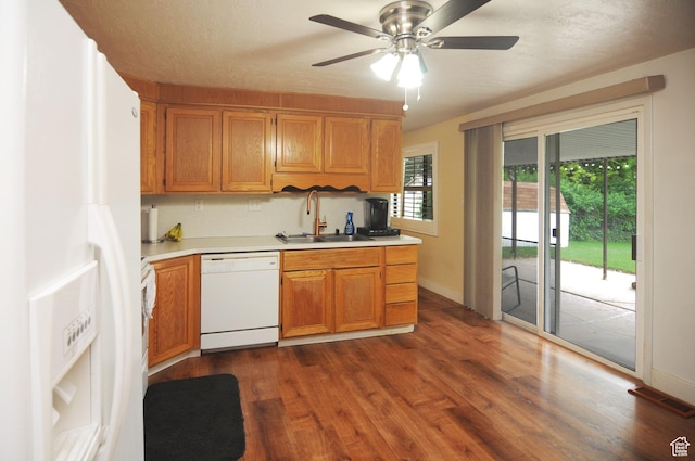 kitchen with white appliances, a sink, light countertops, and dark wood-style floors