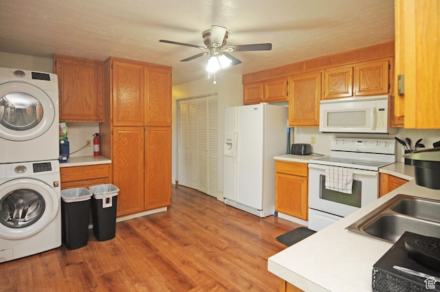 kitchen featuring white appliances, estacked washer and dryer, light countertops, and light wood-style flooring