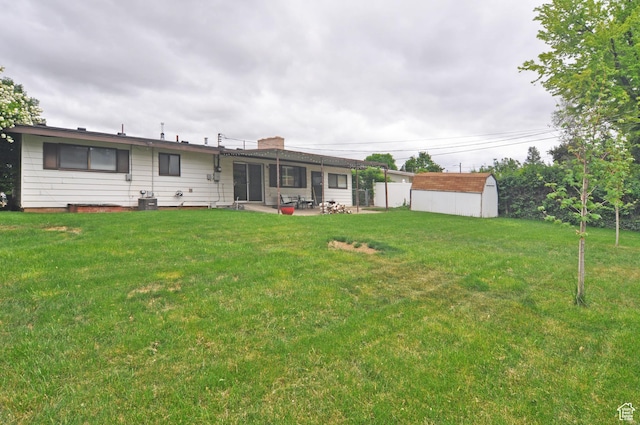 back of house with a patio area, a shed, an outbuilding, a yard, and a chimney