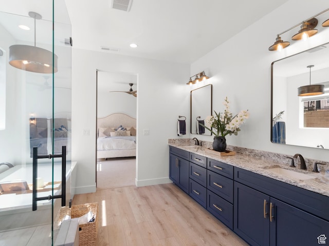 full bath with wood finished floors, a ceiling fan, double vanity, ensuite bath, and a walk in shower