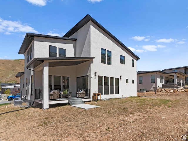 back of house featuring central air condition unit and stucco siding