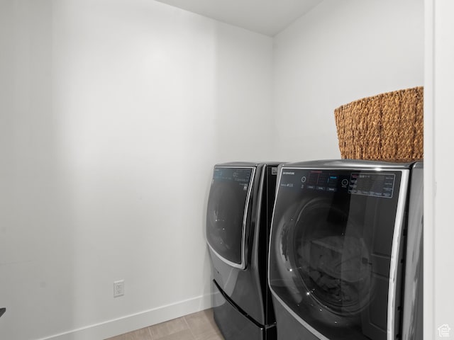clothes washing area with washer and dryer and baseboards