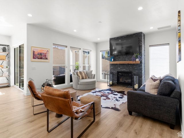 living room featuring light wood-type flooring, a fireplace, and recessed lighting