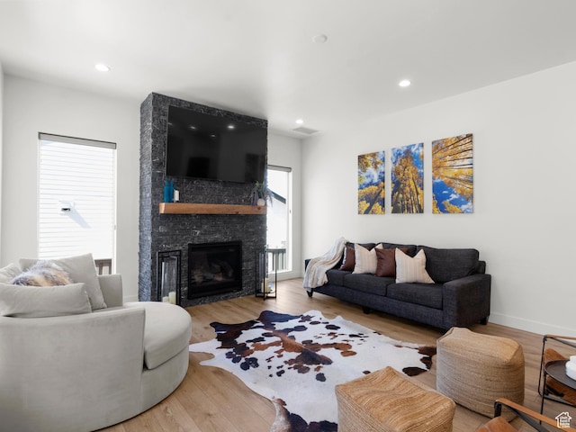 living area featuring wood finished floors, a large fireplace, recessed lighting, and baseboards
