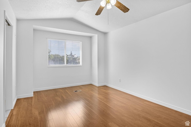 unfurnished bedroom featuring wood finished floors, a textured ceiling, vaulted ceiling, baseboards, and a ceiling fan