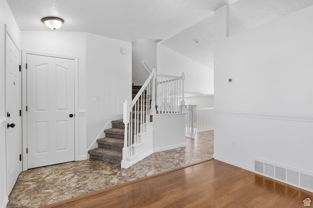 stairs featuring wood finished floors, baseboards, and a textured ceiling