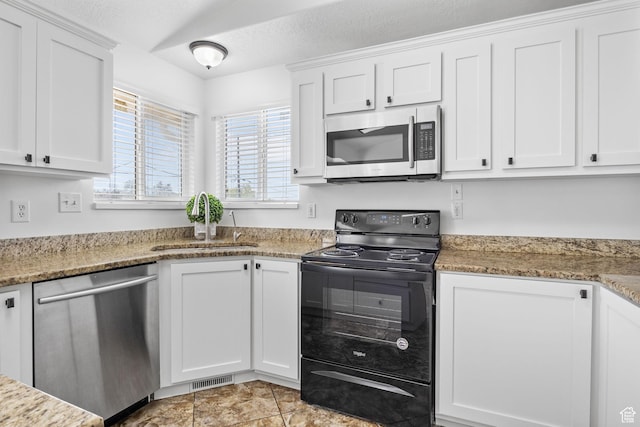 kitchen with stainless steel appliances, a sink, healthy amount of natural light, and white cabinetry