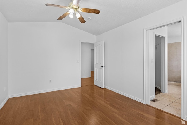 unfurnished bedroom featuring vaulted ceiling, wood finished floors, baseboards, and a ceiling fan