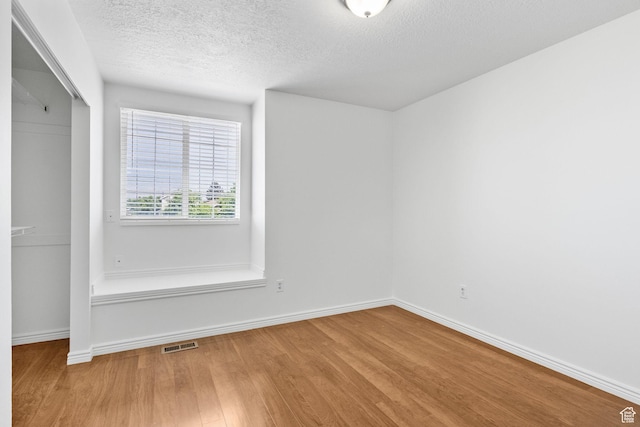 unfurnished room featuring wood finished floors, baseboards, and a textured ceiling