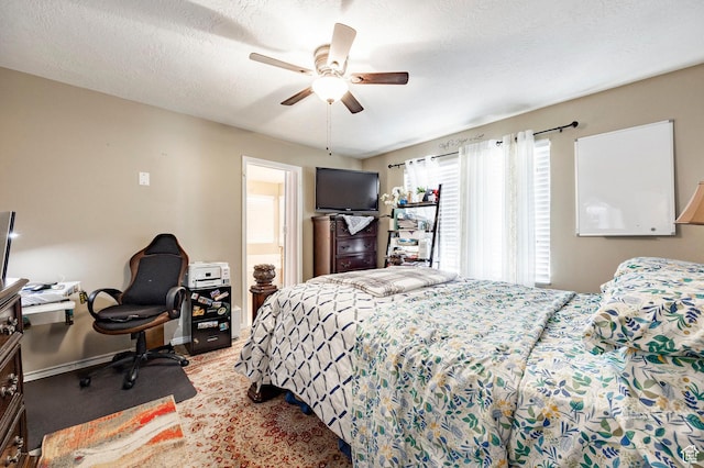 bedroom featuring an office area, ceiling fan, baseboards, and a textured ceiling