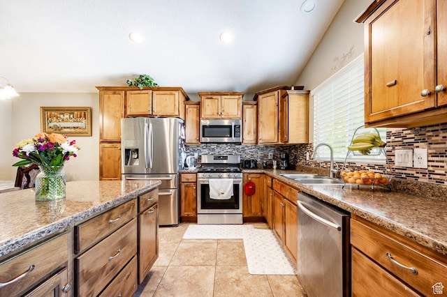 kitchen with stainless steel appliances, a sink, backsplash, brown cabinets, and recessed lighting