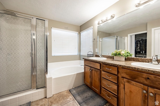 bathroom featuring a stall shower, tile patterned floors, a garden tub, double vanity, and a textured ceiling