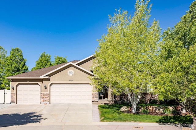 view of front of house featuring stucco siding, concrete driveway, a garage, and stone siding
