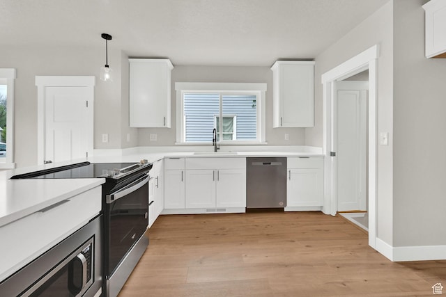 kitchen featuring appliances with stainless steel finishes, a sink, light wood-style floors, and white cabinetry