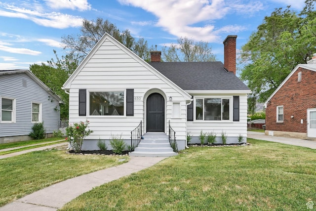 view of front of house featuring a chimney, a front yard, entry steps, and a shingled roof