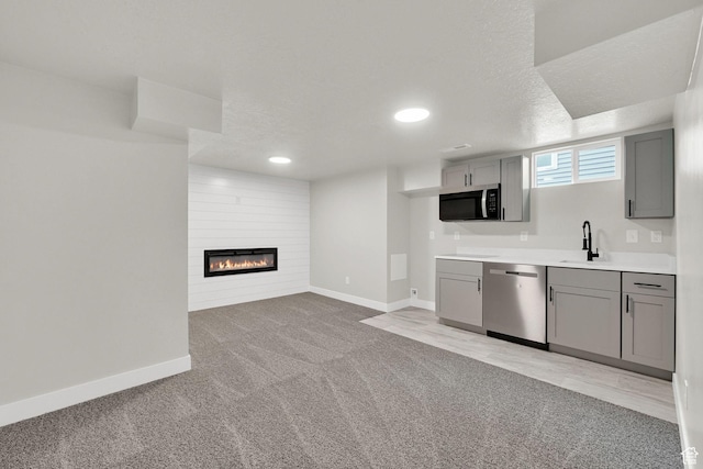 kitchen featuring appliances with stainless steel finishes, gray cabinetry, a sink, baseboards, and recessed lighting