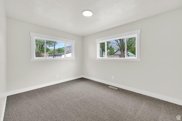 unfurnished room featuring dark carpet, baseboards, and a textured ceiling