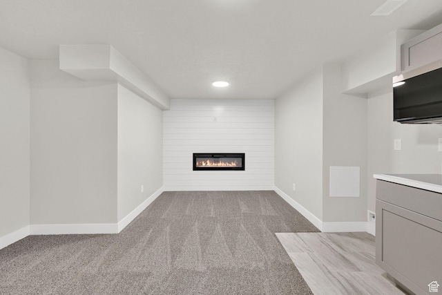unfurnished living room featuring a fireplace, recessed lighting, light carpet, and baseboards