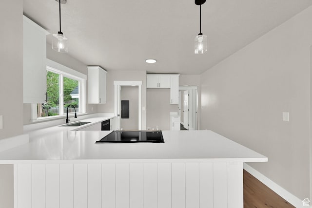kitchen with a sink, black appliances, light countertops, a peninsula, and dark wood-style floors