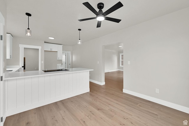 kitchen featuring a ceiling fan, baseboards, white cabinetry, light countertops, and light wood-style flooring