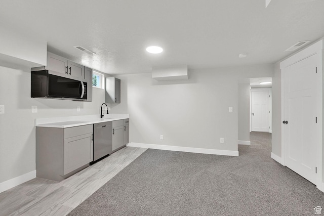 kitchen featuring dishwasher, gray cabinetry, and baseboards