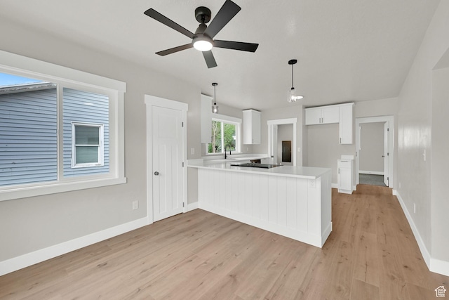 kitchen featuring a ceiling fan, a peninsula, light wood-style flooring, and light countertops