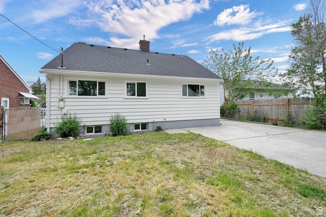 rear view of property with a chimney and roof with shingles