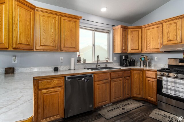 kitchen with appliances with stainless steel finishes, a sink, under cabinet range hood, light countertops, and brown cabinetry