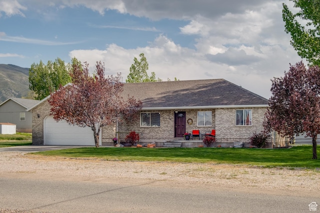 ranch-style home featuring concrete driveway, a garage, brick siding, a front lawn, and roof with shingles