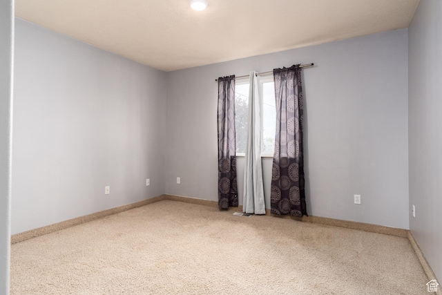 empty room featuring carpet and baseboards