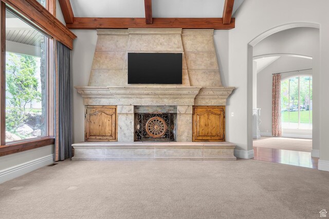 81 E Lone Hollow Dr S, Sandy, UT 84092 - unfurnished living room featuring carpet, baseboards, beamed ceiling, arched walkways, and a fireplace