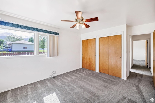 unfurnished bedroom with carpet, multiple closets, and a ceiling fan
