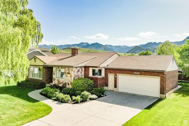 view of front of property featuring an attached garage, a front lawn, concrete driveway, and a mountain view