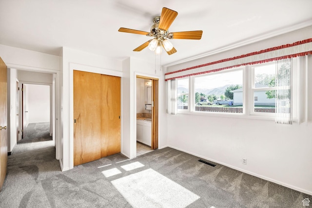 unfurnished bedroom with carpet, a closet, ceiling fan, and baseboards