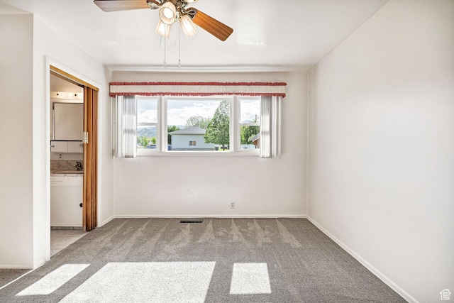 carpeted spare room featuring a ceiling fan and baseboards