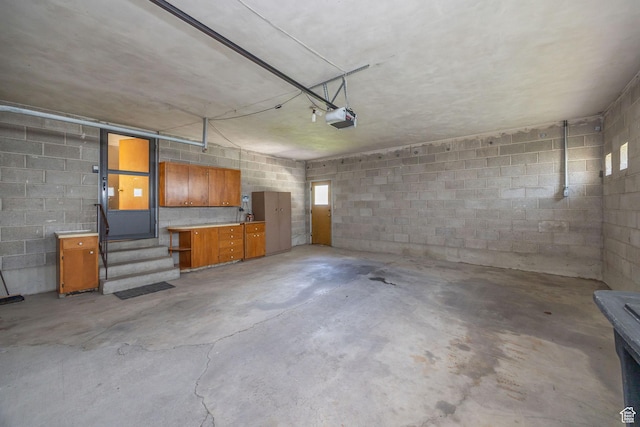 garage with a garage door opener and concrete block wall