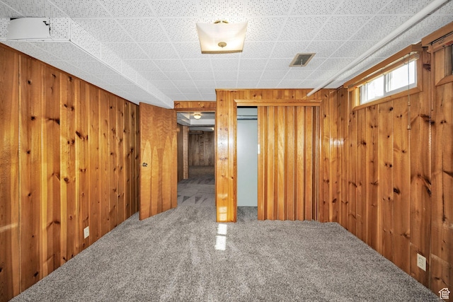 basement featuring carpet flooring and wooden walls