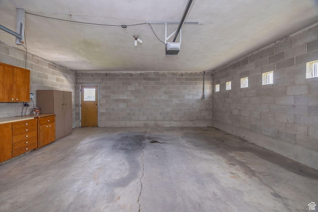garage with a garage door opener and concrete block wall