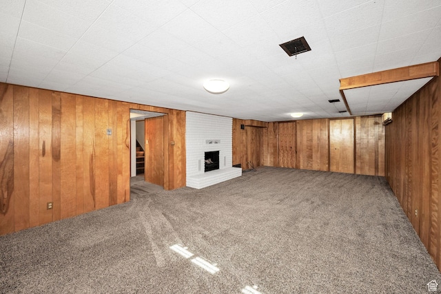 finished basement with carpet, stairs, wood walls, and a brick fireplace