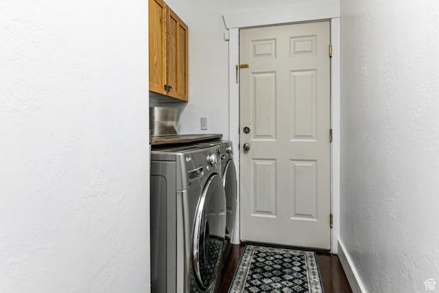 laundry area with cabinet space, washer and dryer, dark wood-style floors, a textured wall, and baseboards