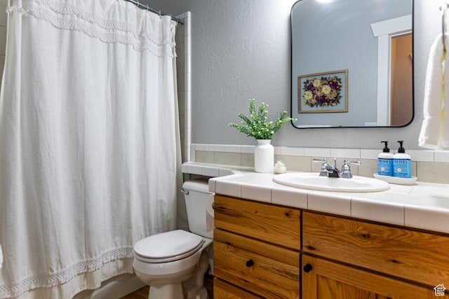 bathroom with toilet, vanity, a shower with curtain, and a textured wall