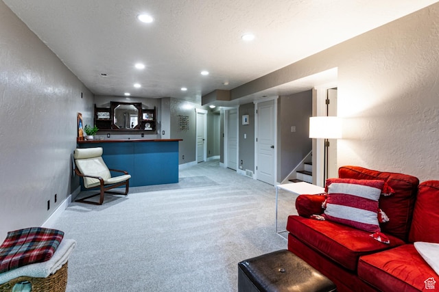 living room with a textured wall, light carpet, stairs, recessed lighting, and baseboards