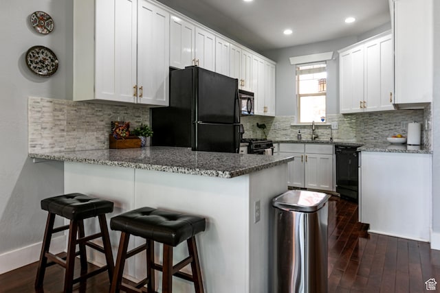 kitchen featuring black appliances, a peninsula, dark wood-style flooring, white cabinets, and recessed lighting
