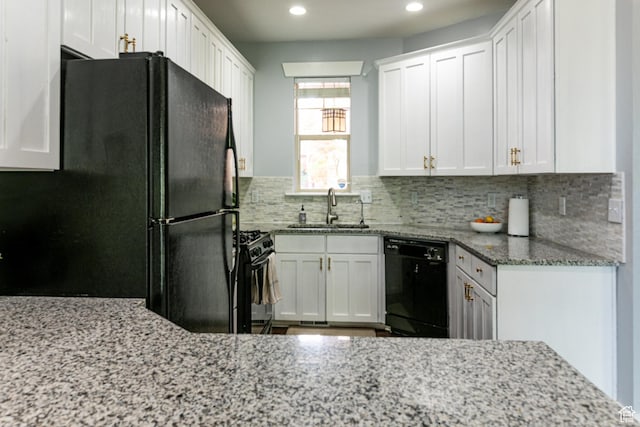 kitchen with black appliances, a sink, backsplash, light stone counters, and recessed lighting