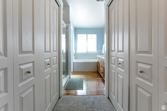 full bath featuring a garden tub, a shower stall, hardwood / wood-style flooring, and a closet