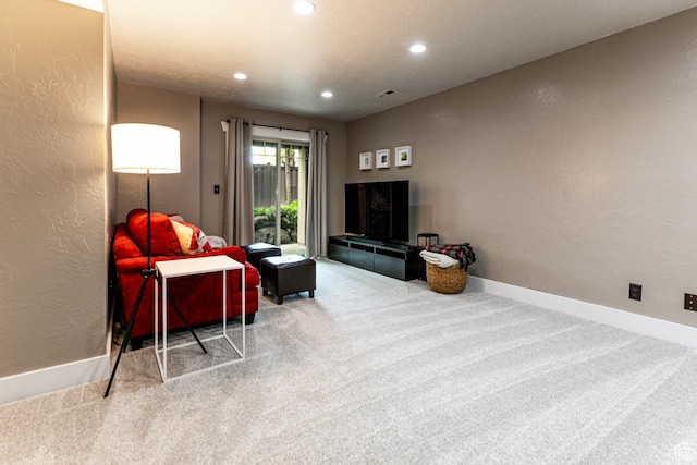 carpeted living area featuring a textured wall, recessed lighting, and baseboards